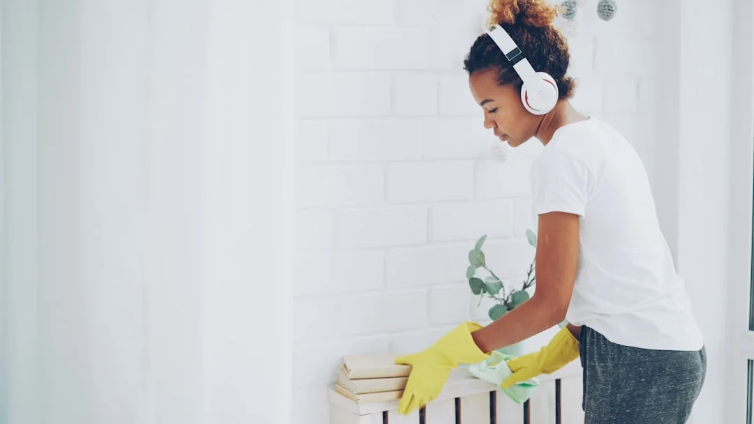 Minimalist room with a person cleaning a chair using a sponge and cleaning product.